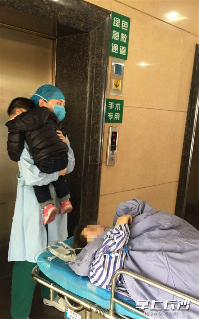 护士汤洁抱起手术患者的宝宝，麻醉师拍下温暖一幕。