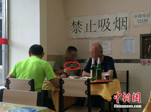 ↑资料图：北京某餐馆，一男子在“禁止吸烟”的标识下抽烟。中新网 邱宇 摄