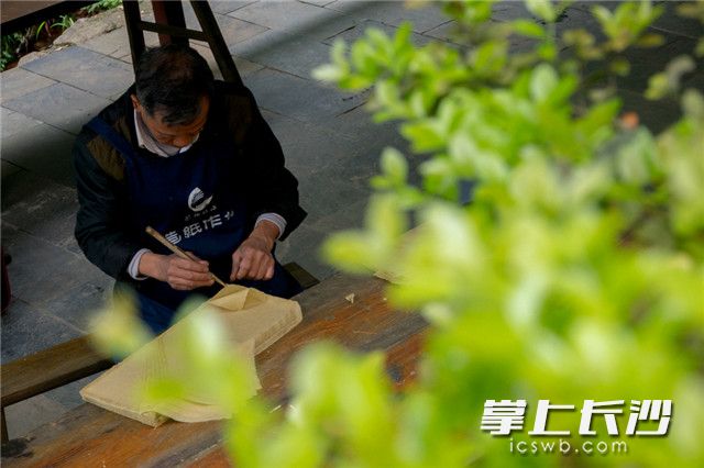 纸张榨干后，刘俊杨用竹镊小心翼翼挑起纸的边角，将纸张一张张分离出来。