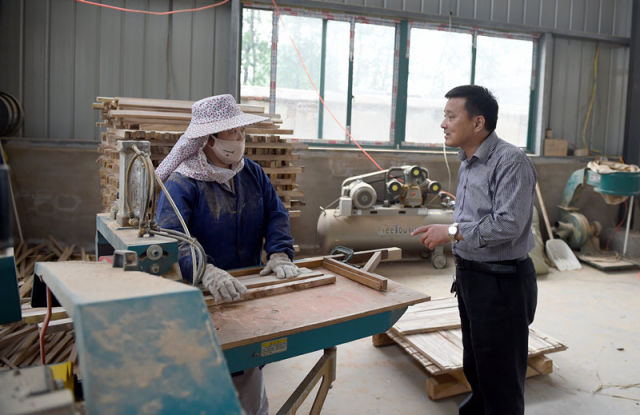 这是安徽省霍邱县长集镇七里棚村第一书记罗炜（右）正在查看村内的家具厂生产情况（5月23日摄）。新华社记者 郭晨 摄