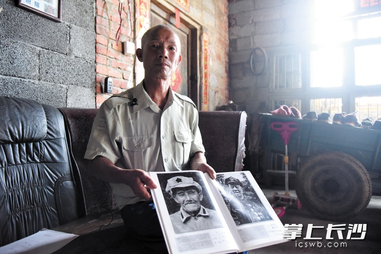 　　邹贤松向记者展示他父亲邹盛栋（左）的照片。老红军邹盛栋负伤后被侗族妇女收留，并收为义子。