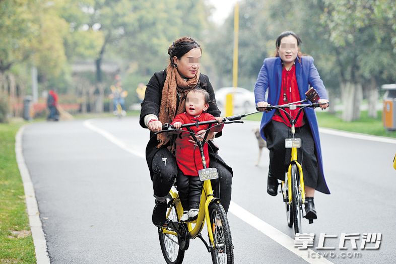 有家长骑车时让孩子站在共享单车横梁上，容易发生意外。长沙晚报记者 王志伟 摄