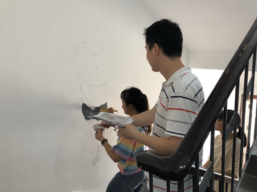 湖南工业职学院党员师生正在进行创意墙绘。