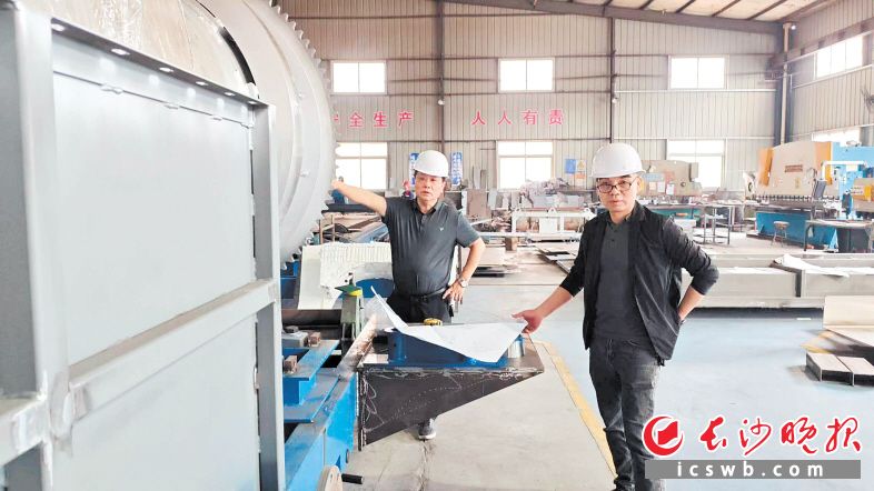 姜国明（左）和文小洪在车间检查调度生产情况。企业供图