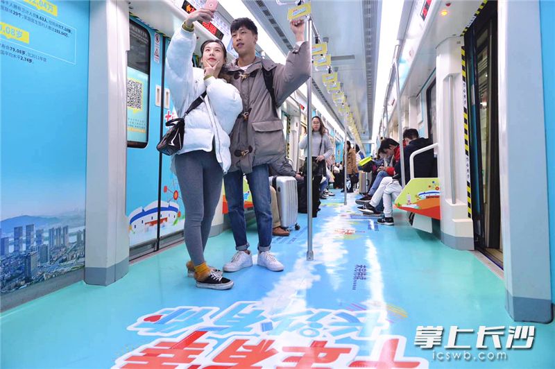 一对情侣在“开往幸福的长沙号”地铁专列车厢自拍。