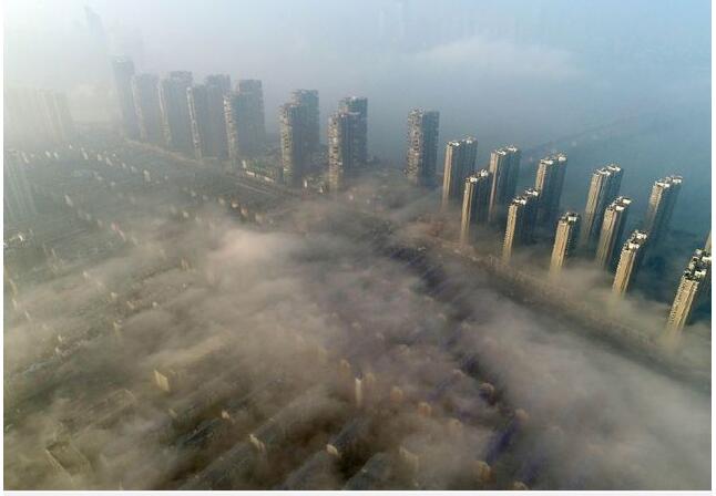 当天我省大部分地区天气转晴，出现大雾天气。从空中俯瞰，城区建筑高楼在大雾中若隐若现。
