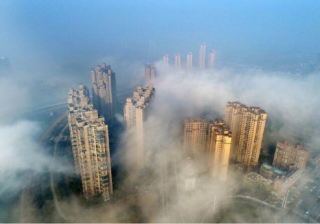 从空中俯瞰，城区建筑高楼在大雾中若隐若现，看似海市蜃楼，如梦似幻宛若人间仙境。