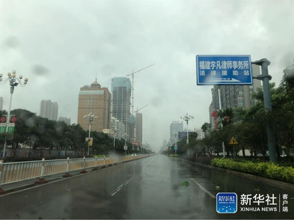 受台风“玛莉亚”影响，11日上午，福清市区风雨大作，城区道路车辆稀少，行人和骑行者艰难前行。