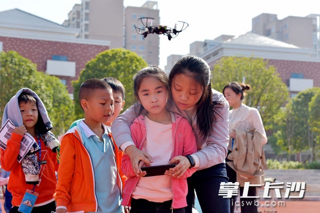 工作人员教孩子们通过手机，操控无人机。周秋燕 摄