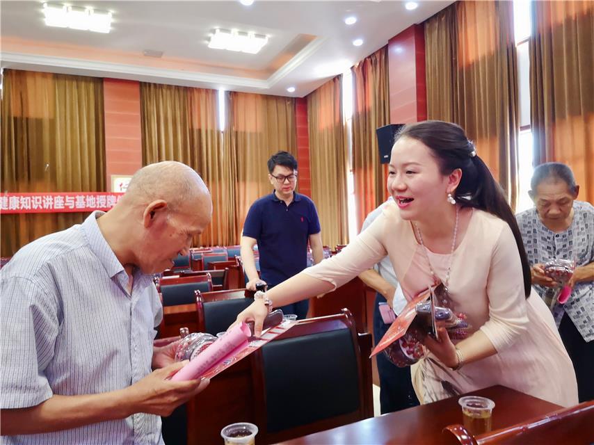 天丹公益基金博士服务团团长吴丹（右一）为敬老院老人们发放多功能按摩棒。
