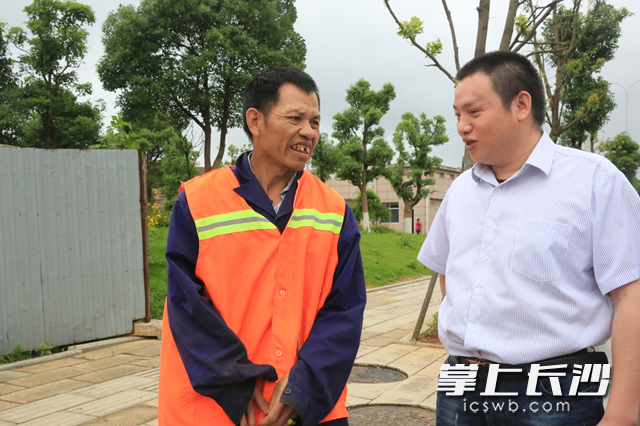 宁乡欣云保洁公司总经理贺瞻（右）正在与残疾员工杨国强交流。