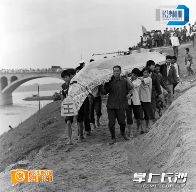 1985年6月22日，参加浏阳河端午龙舟赛的群众抬舟下水。