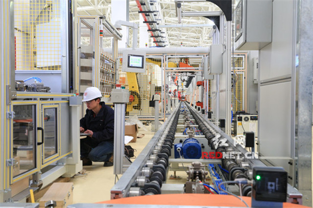 在长沙经开区广汽三菱汽车有限公司发动机工厂厂房，工作人员正在调式机器设备。