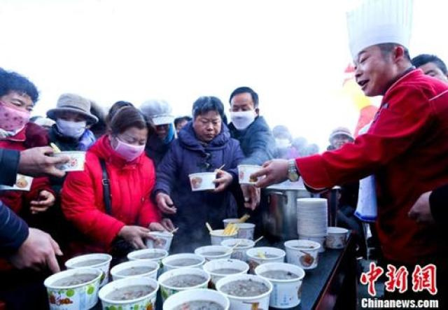 资料图：甘肃张掖厨师在给市民盛免费腊八粥。