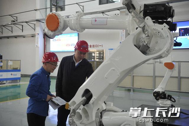 杨漾(右)查看机器人关键部件，与工程师交流技术细节。长沙晚报全媒体记者 余劭劼 摄