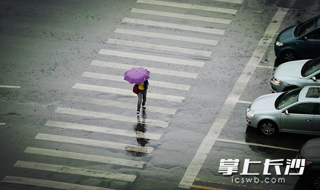 一市民小心的在雨中的路面走过。