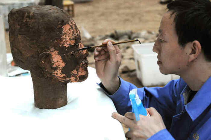 2010年11月25日，在兵马俑发掘现场，工作人员在俑头上涂加固剂。 新华社发（张天柱 摄）