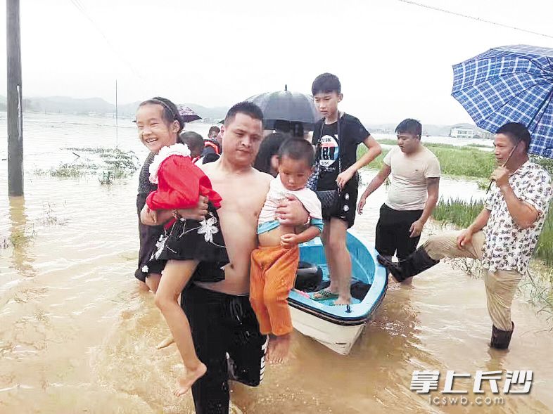 7月1日，唐伟将一船人救到安全区域后，把其中两名小孩抱了下来。随后，他又返回村里救被困群众。受访者供图