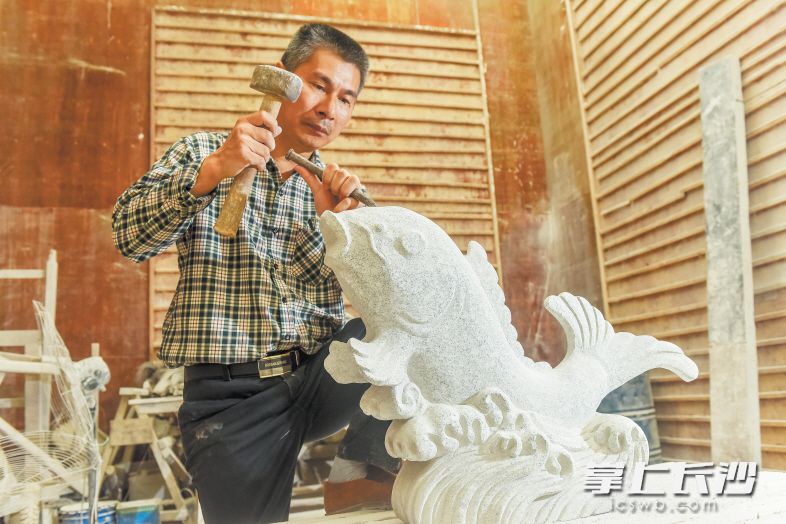 石山脚下，47岁的周旭正在雕刻一座佛像，这里不但是他的厂房，同时也是丁字湾街道农民麻石雕刻免费培训基地。