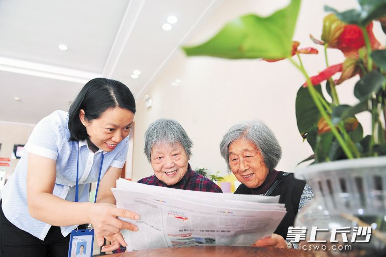雨花区社会福利中心的工作人员正在陪老人读报。