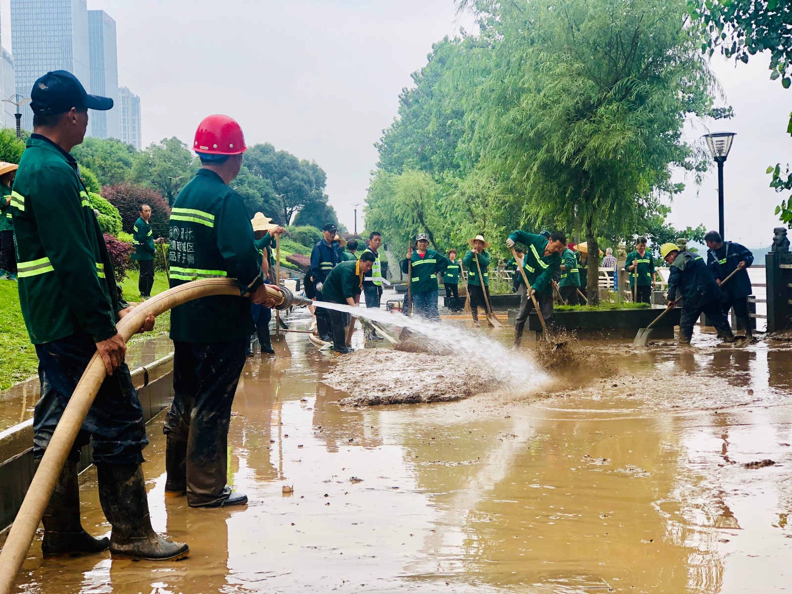 湘江风光带风帆广场附近，开福区园林绿化维护人员用高压水龙冲刷洪水留下的厚积淤泥。长沙晚报全媒体记者 李卓 摄