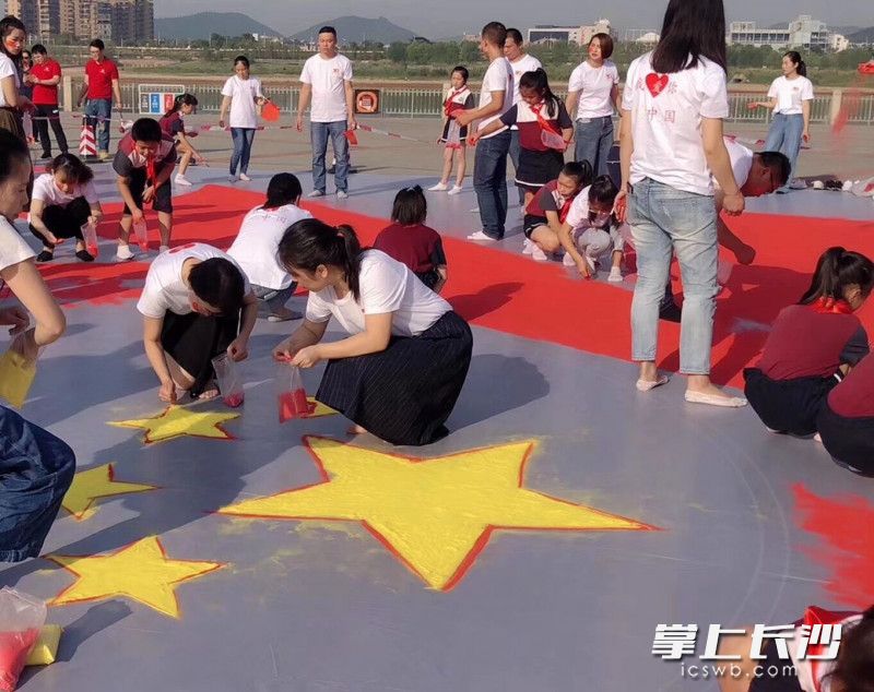 老师、家长和孩子们一起动手绘沙画。