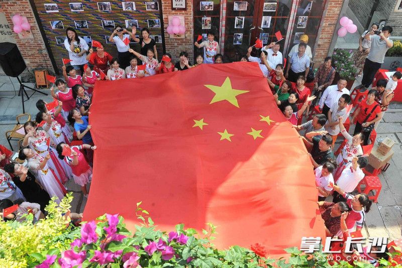 9月29日，开福区连升街社区在富有老街气质的北正街舒展国旗，唱响《五星红旗迎风飘扬》。