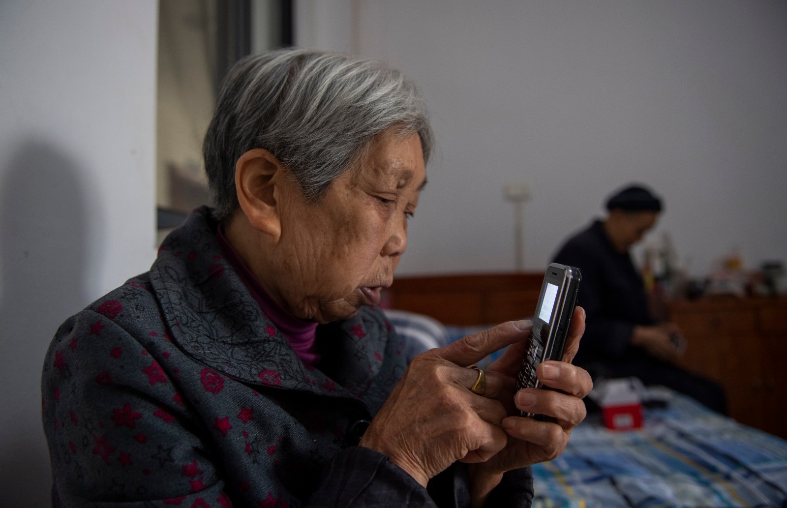 一位老人正在使用刚刚收到的新手机。