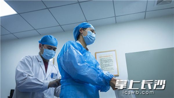 助理李医生正在为杨丽红穿戴一次性手术衣。