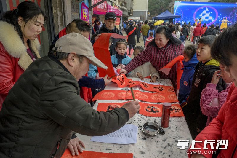 文化志愿者挥毫泼墨，为村民义务书写吉庆村民，受到大伙热捧。