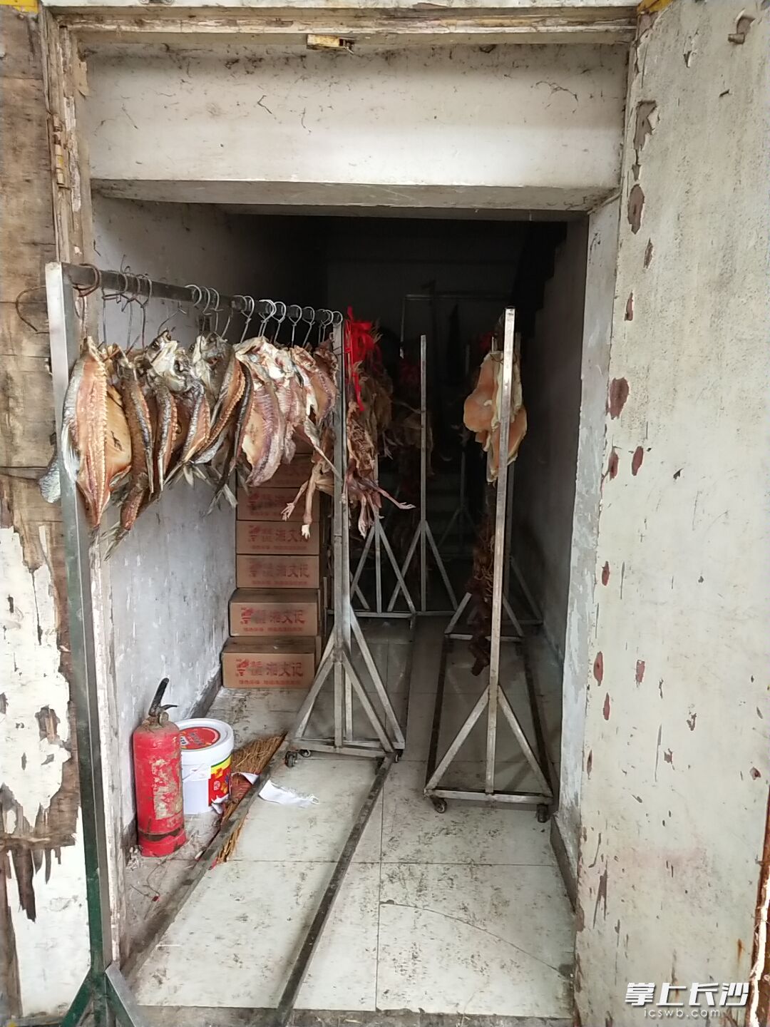 湘村柴房湘菜馆后厨的应急疏散通道和楼梯处均存放了众多腊制品和熏制设备等。

