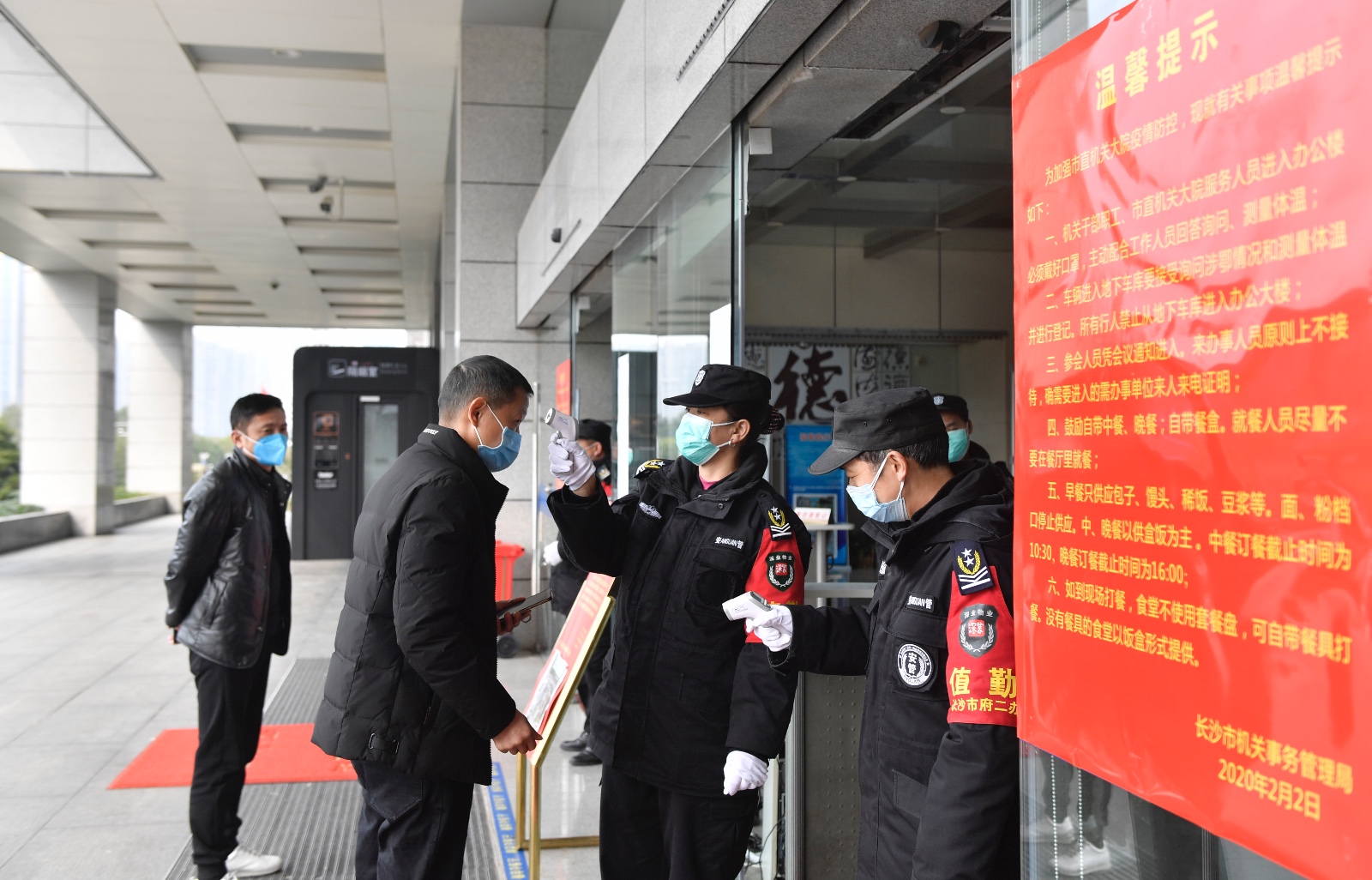 安保人员正在对前来办理业务的市民进行体温检测。
