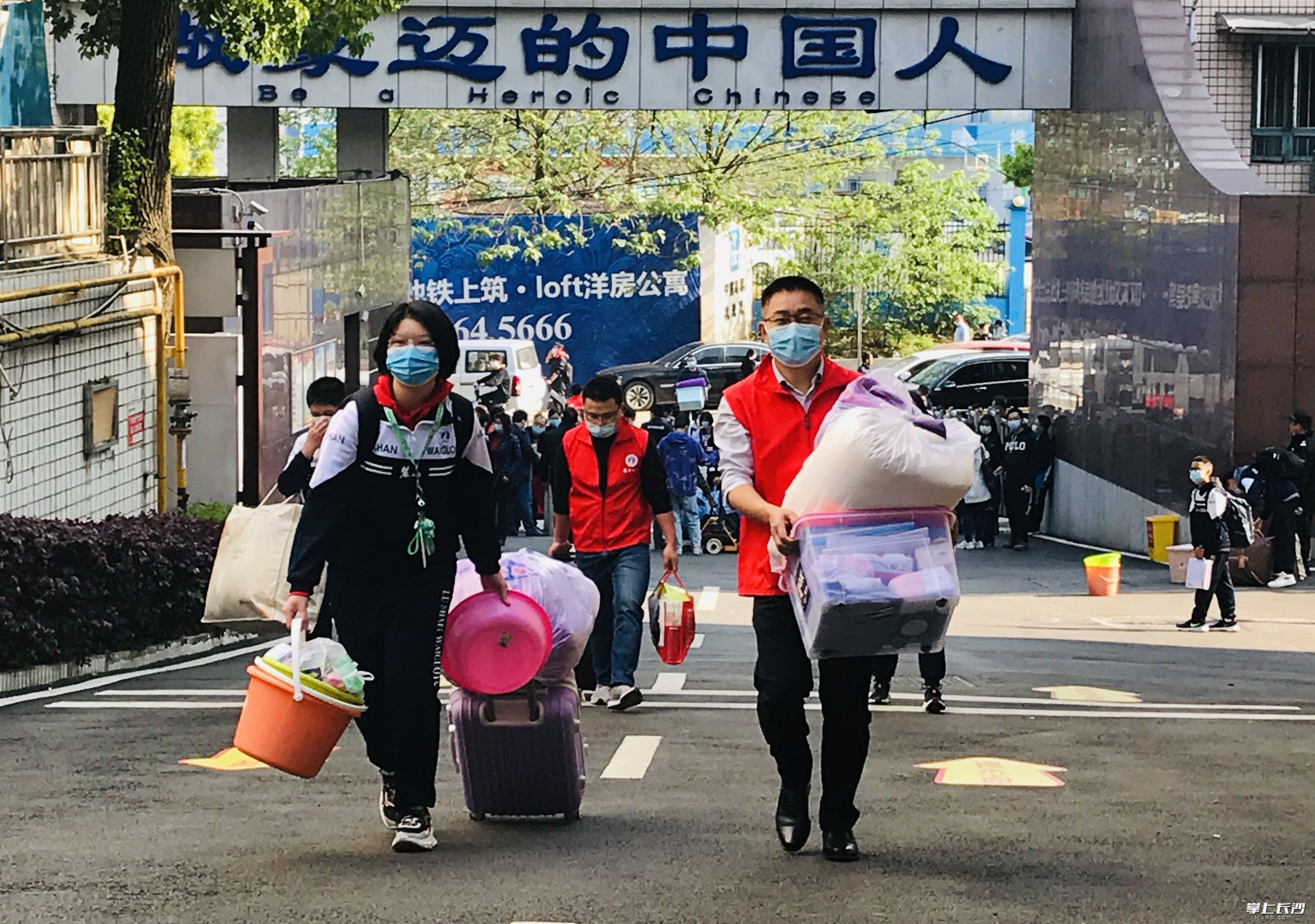 因为家长不能入校，老师做志愿者，图为麓山外国语实验学校校长张辉为学生搬运行李。