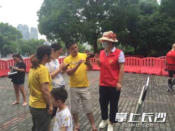 游客向穿红马甲的志愿者求助。