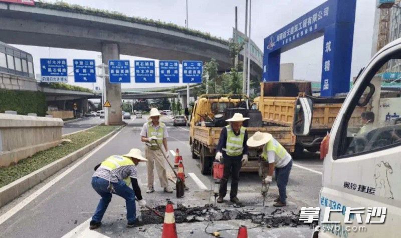 市政工人对湘府路车行道路面破损进行修补。