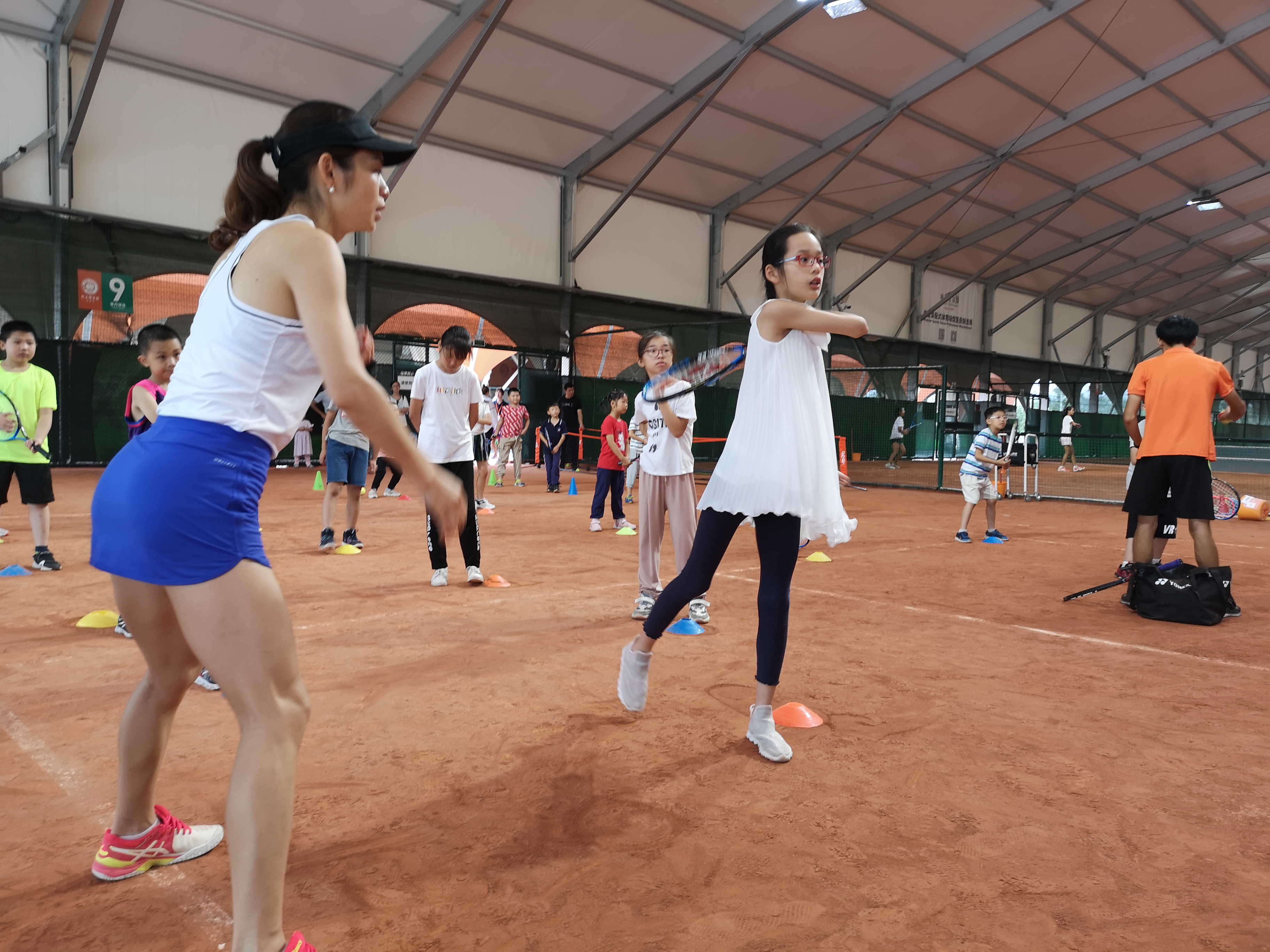 20日上午，位于望城区的月亮岛法网-罗兰·加洛斯红土网球公园内，孩子们在教练的指导下击球。