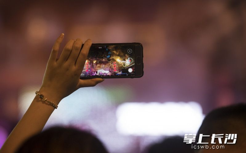 7月31日晚，“湘SHOW•0731，不燃何解”——首届长沙本土青年潮流音乐市集在长沙坡子街火宫殿（总店）激情开唱，一位游客正拿着手机拍摄。图片均为长沙晚报全媒体记者 邹麟 摄