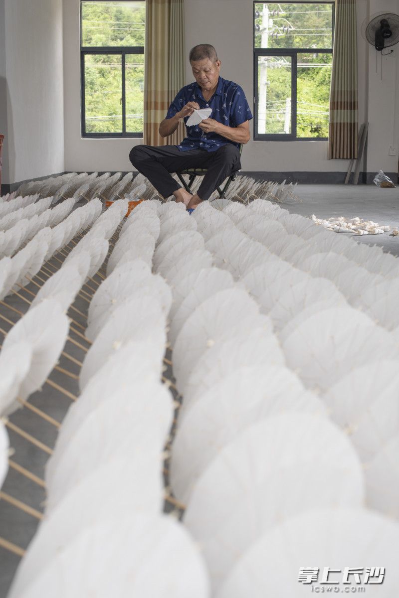 达兴工艺品厂扶贫车间里，贫困户廖尚荣正在制作小伞工艺品，经过培训，他一天能做近200个，每天收入120元左右。