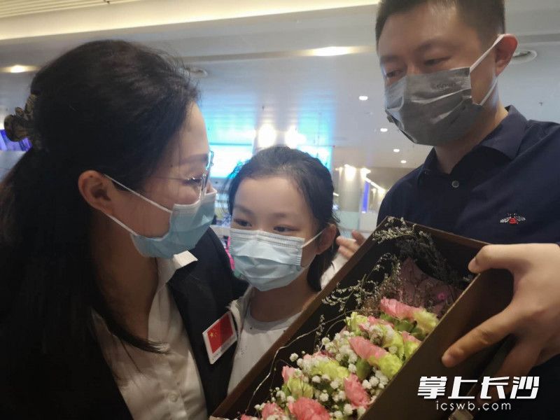 援塞医疗队员、湖南省肿瘤医院内科副主任医师何奕（左）一家三口喜相拥，女儿向妈妈献上最美的花朵。