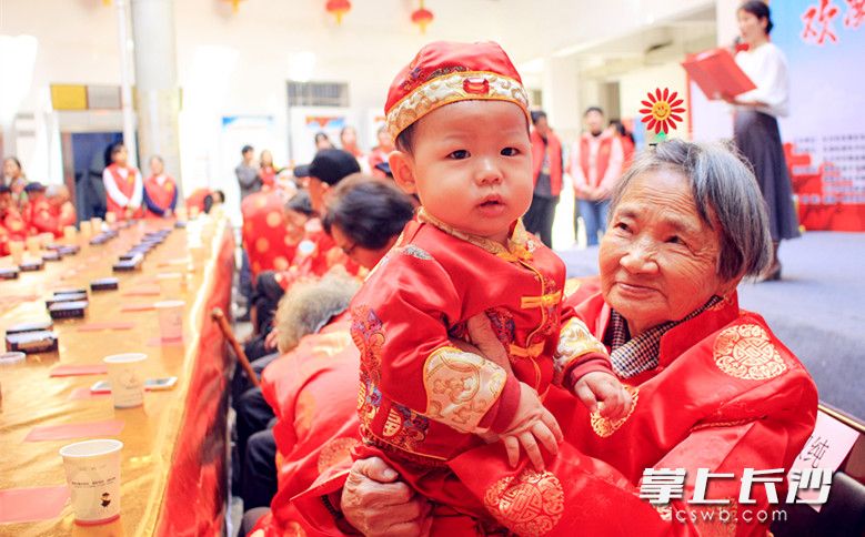 受邀参与社区重阳节家宴活动，身着唐装的老人带着小孩很开心。