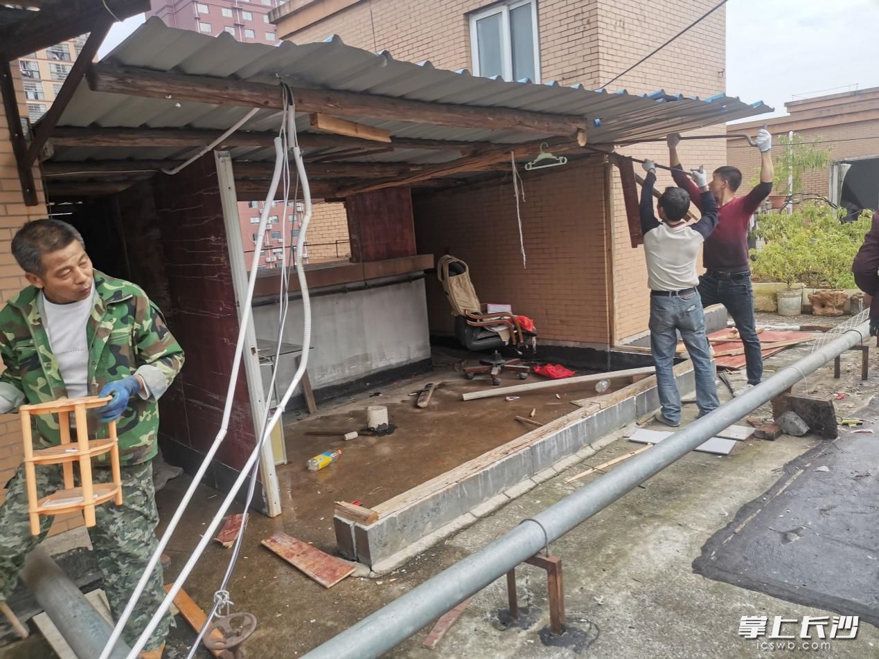 工作人员正拆除居民私自搭建的棚子。