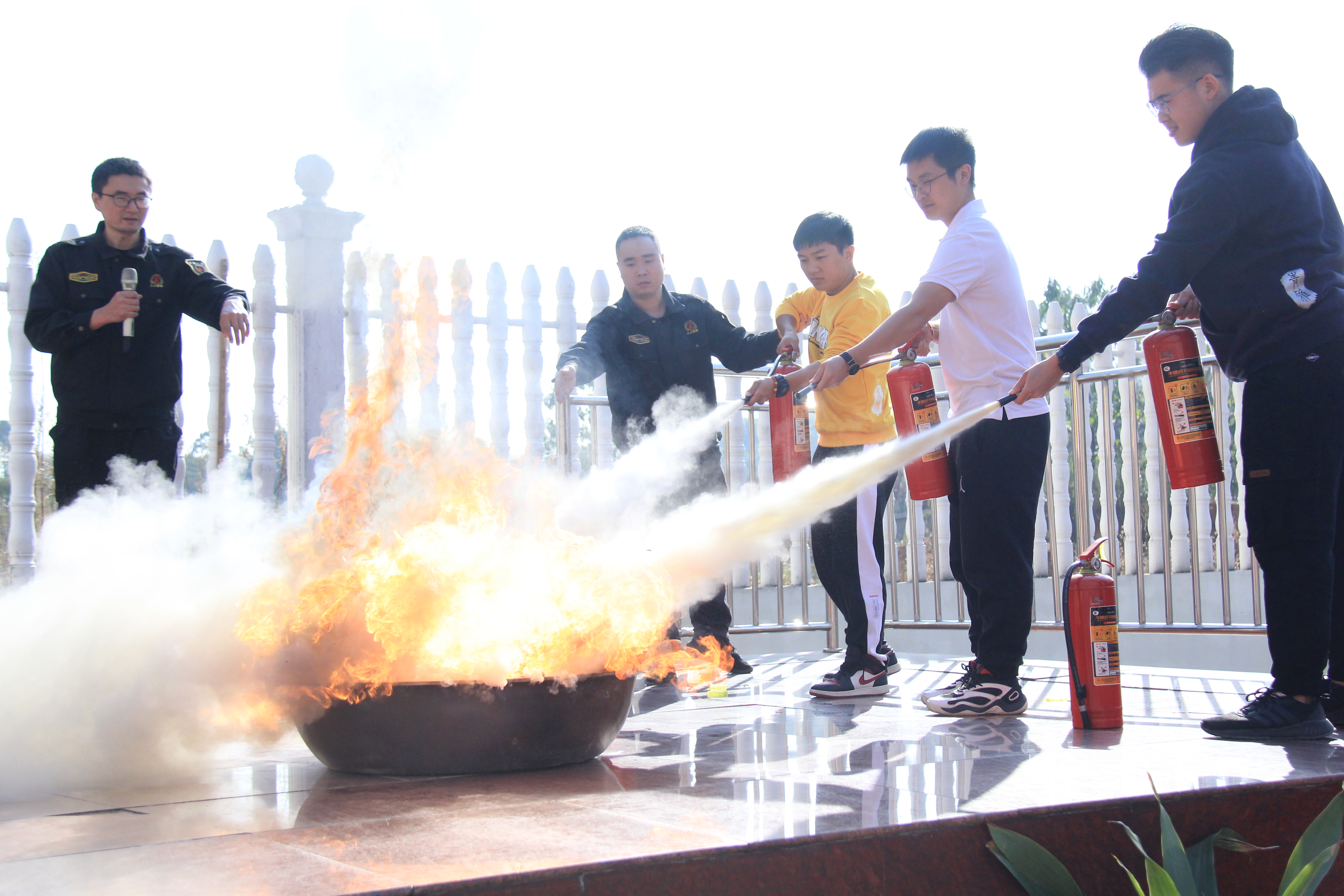青雅丽发学校的老师们在教官指导下用灭火器灭火。
