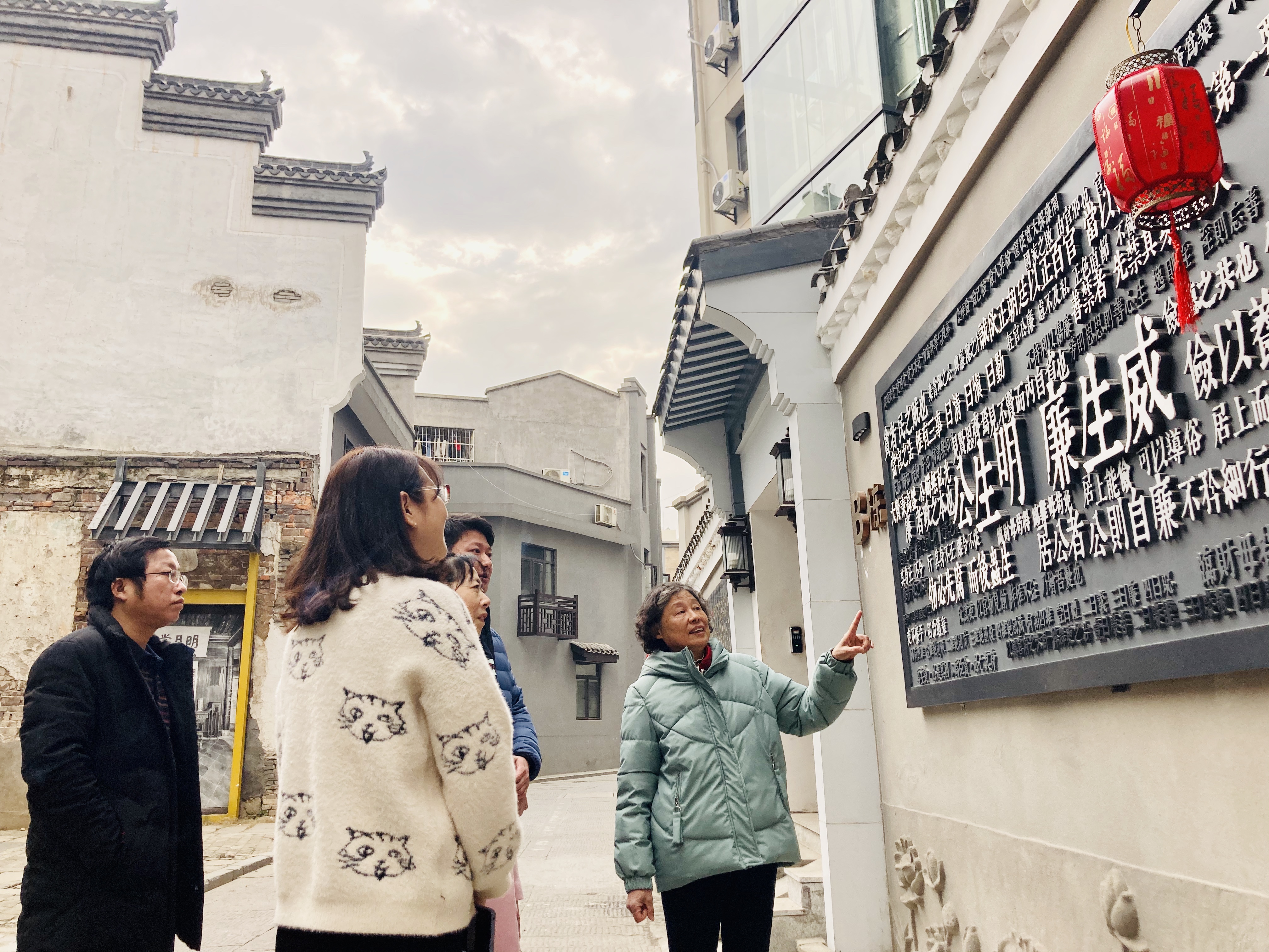 杨云（右一）在连升街“廉”墙前给社区工作人员和游客讲先辈诚信自守的老街往事。 均为长沙晚报全媒体记者 李卓 摄
