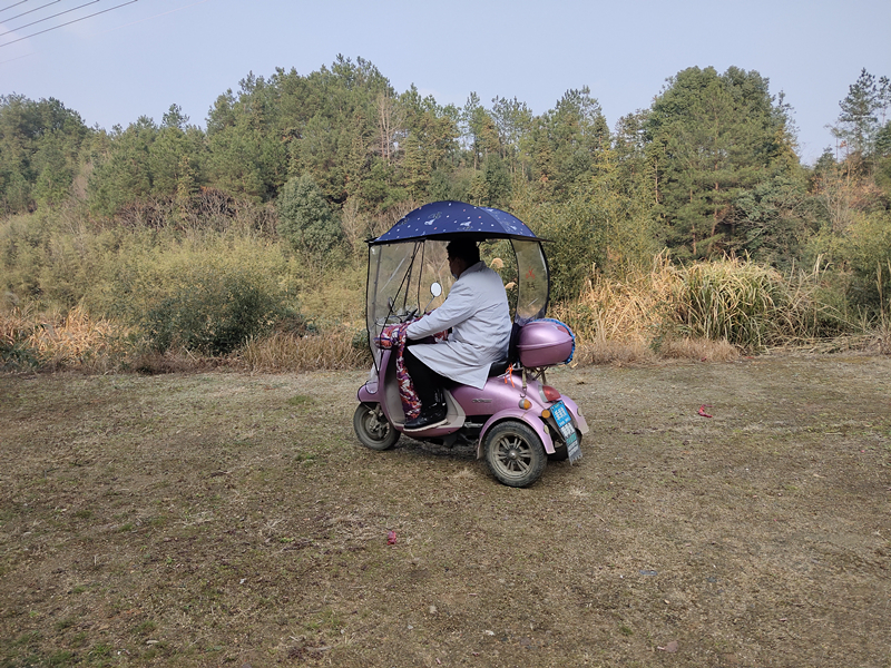 村医周白龙骑着他淡紫色的电动三轮车走村串户，宣传防疫知识。受访者 供图