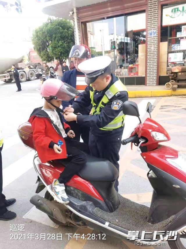 交警在路面巡查劝导中为摩托车小乘客戴好安全头盔。受访者供图