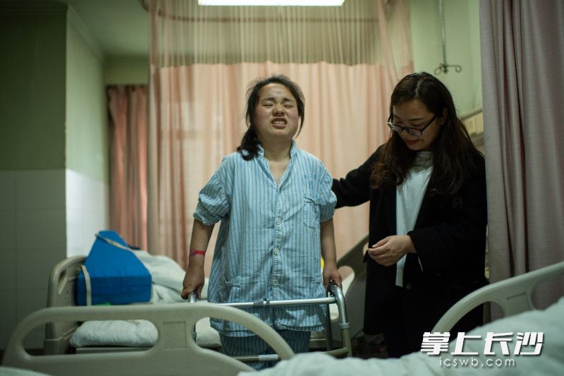 在中南大学湘雅二医院骨科病房里，吴添春在妹妹的搀扶下进行康复的练习。