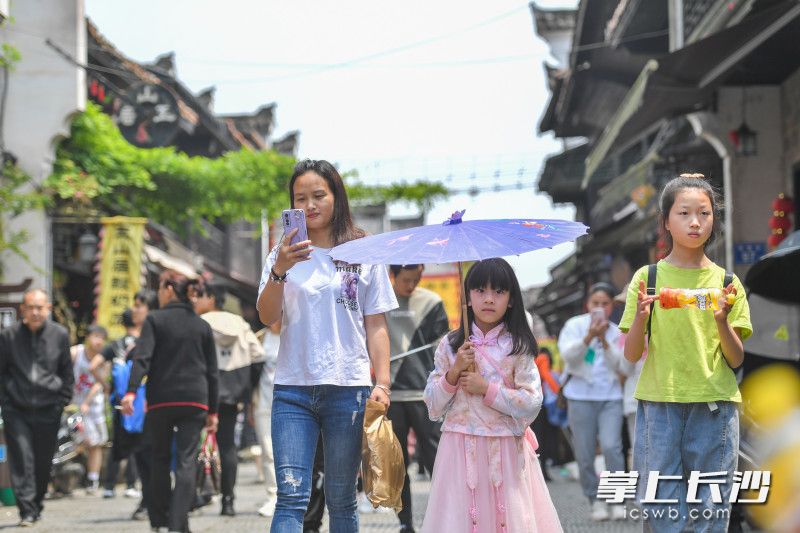 一位小女孩穿着古装打着油纸伞漫步在靖港古镇。长沙晚报全媒体记者 邹麟 摄