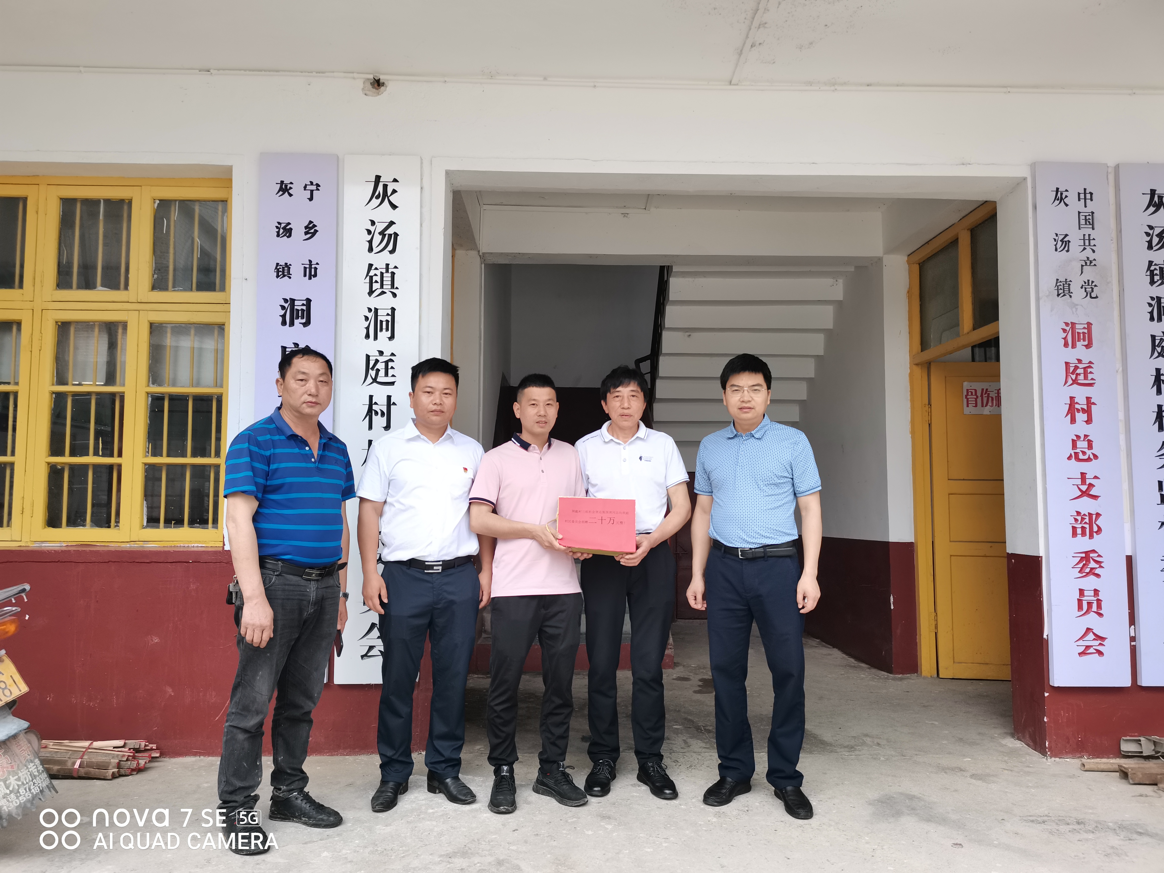 今日，张国清（右二）将20万元现金交到洞庭村党总支书记张文初（左三）手上。