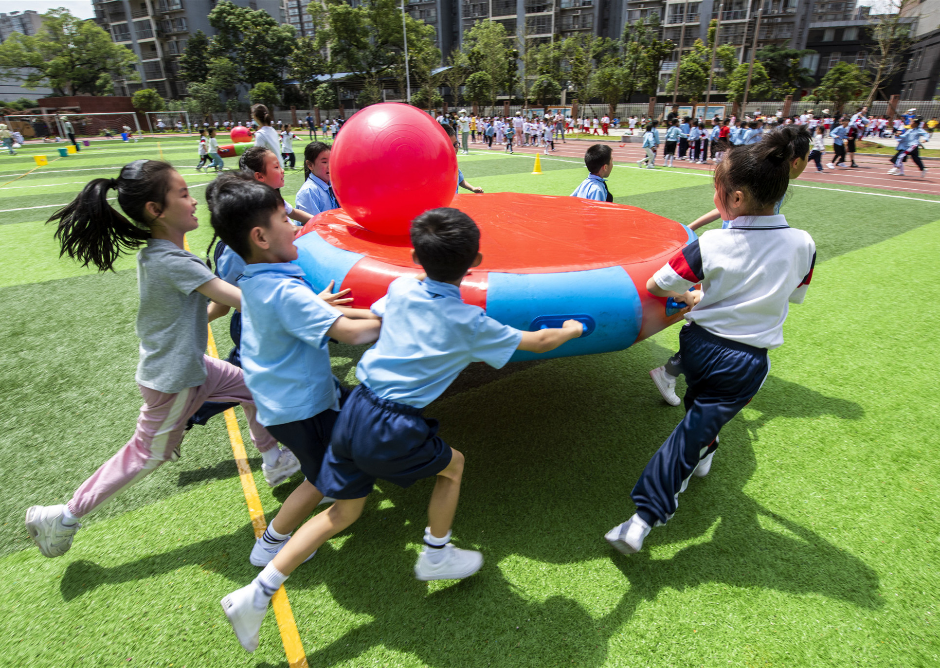 “祖国腾飞”项目中，10名同学共同托起红色小球，在绿色草地上奔跑。