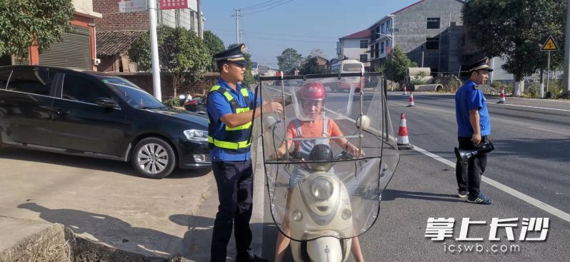 执法人员正在帮骑电动车路人戴好安全帽。